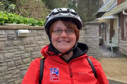 Blind veteran Sheila wearing a cycling helmet and red Blind Veterans UK jacket