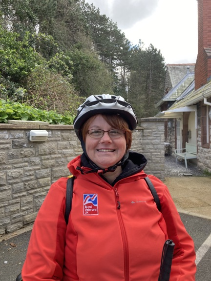 Blind veteran Sheila wearing a cycling helmet and red Blind Veterans UK jacket
