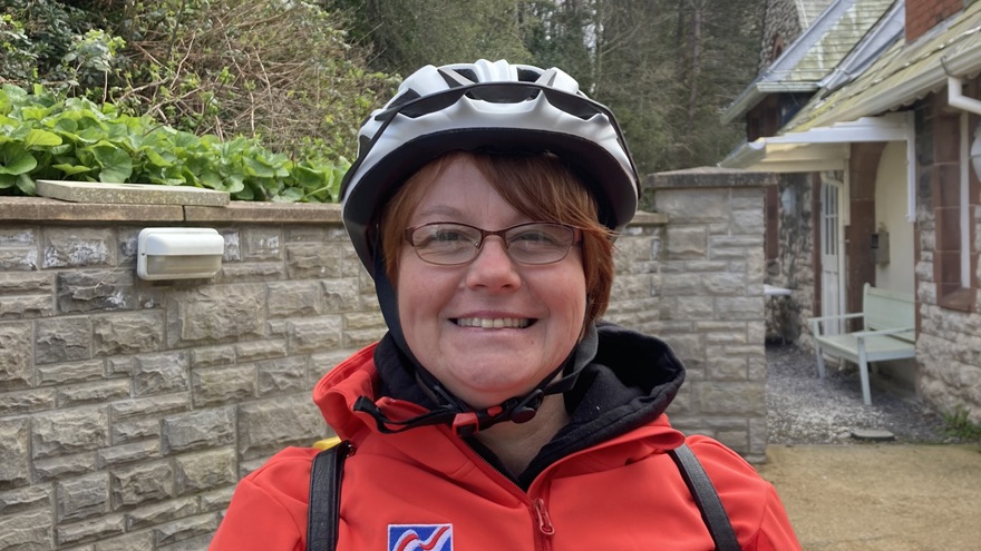 Blind veteran Sheila wearing a cycling helmet and red Blind Veterans UK jacket