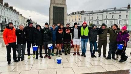 Group dressed as Vikings standing with collection buckets in front of the Llandudno War Memorial at the end of the challenge
