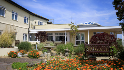 Princess Marina House, with a beautiful garden at the entrance featuring greenery and orange flowers