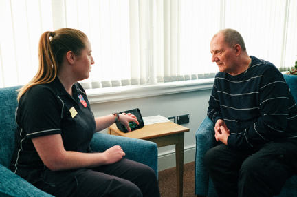 Rhian, a Wellbeing Specialist demonstrates the new Amazon Alexa at the Llandudno Centre to Blind Veteran Jules