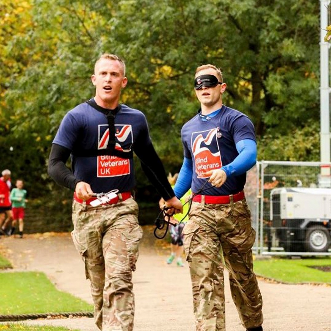 Charity supporter Nephi, running blindfolded, holding a piece of rope connected to his guide, who runs slightly ahead of him.