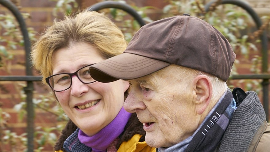 A headshot of blind veteran Colin and his daughter smiling at the camera as they walk