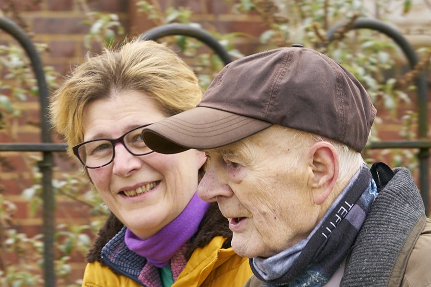 A headshot of blind veteran Colin and his daughter smiling at the camera as they walk