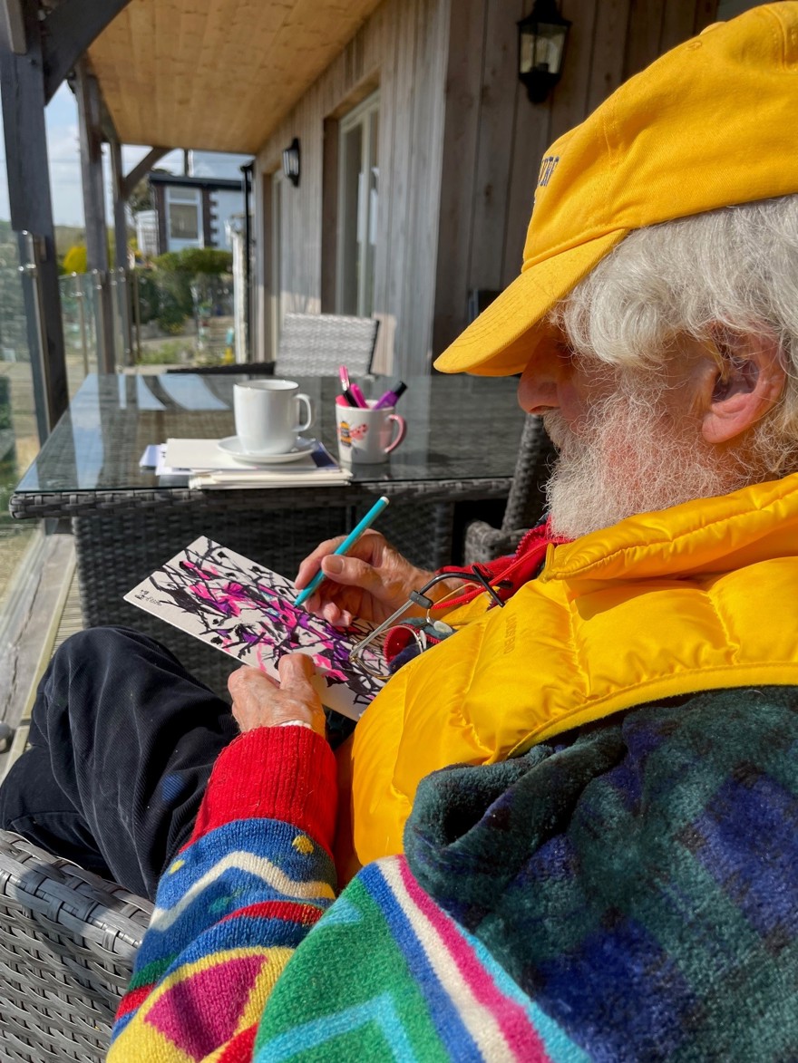 Blind veteran Philip is sitting on a porch and drawing on a piece of card