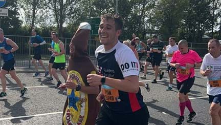 Ryan wearing a Blind Veterans UK t-shirt and running next to a man in a beer bottle costume