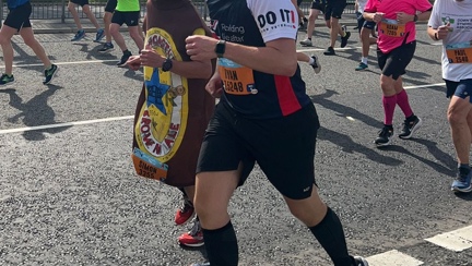 Ryan wearing a Blind Veterans UK t-shirt and running next to a man in a beer bottle costume