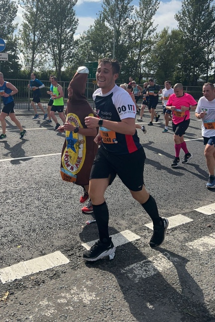 Ryan wearing a Blind Veterans UK t-shirt and running next to a man in a beer bottle costume
