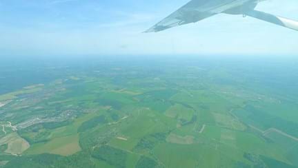 Image shows the wing of the plane and the fields below