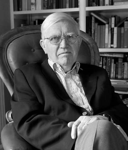 A black and white photo of Dr Zbigniew Pelczynski OBE sitting in chair with bookshelf in background