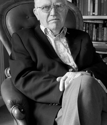 A black and white photo of Dr Zbigniew Pelczynski OBE sitting in chair with bookshelf in background