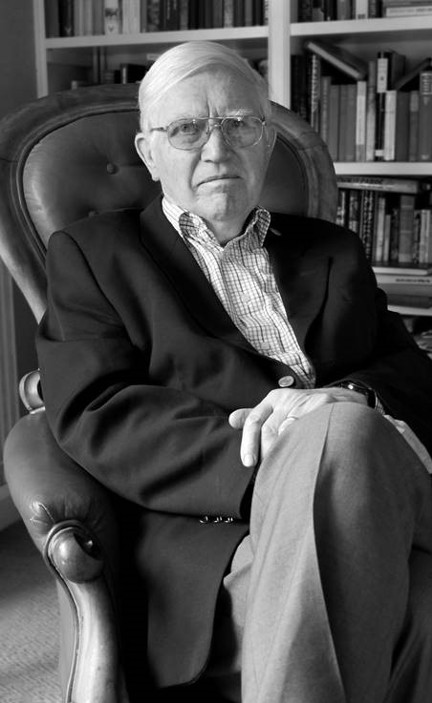 A black and white photo of Dr Zbigniew Pelczynski OBE sitting in chair with bookshelf in background