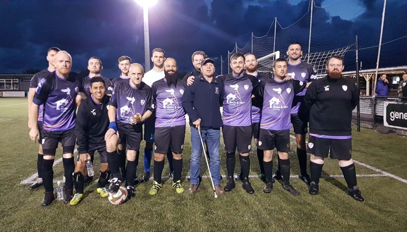 North Wales Dragons team on the pitch wearing their kit with blind veteran Billy stood amongst them