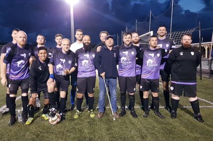 North Wales Dragons team on the pitch wearing their kit with blind veteran Billy stood amongst them