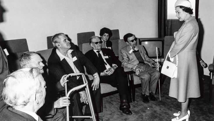 Her Majesty The Queen, speaking to a small group of seated blind veterans