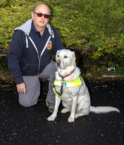 Mark kneeling down next to his guide dog