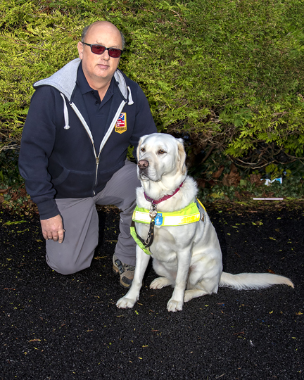 Mark kneeling down next to his guide dog