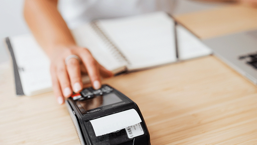 A photo of a cashier using a card machine to print a receipt 