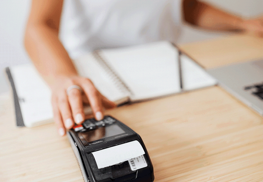 A photo of a cashier using a card machine to print a receipt