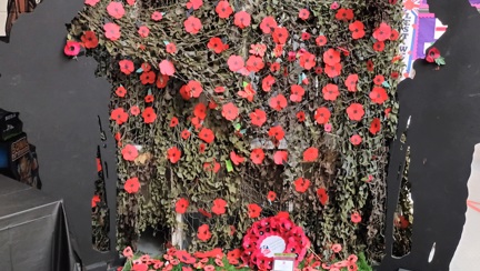 A Blind Veterans UK wreath in front of shower of poppies and two WWI soldier cut outs