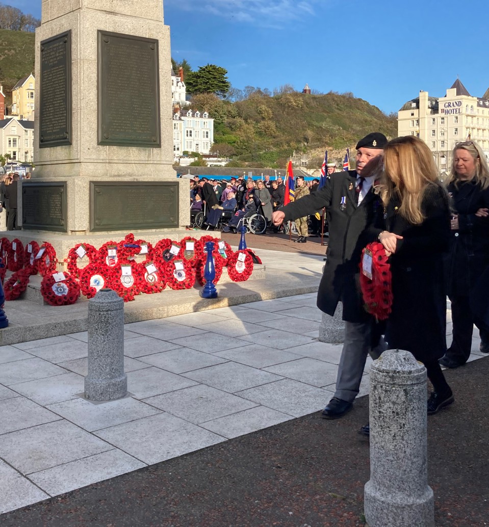 Blind veteran Billy Baxter approaching the Llandudno Town War Memorial to lay a wreath on Remembrance Sunday, accompanied by wreath gifter Kelly of Tom Owens and Sons.