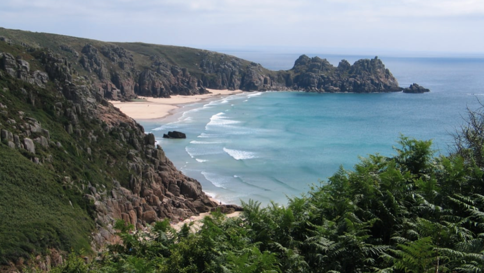 Porthcurno Beach surrounded by high cliffs