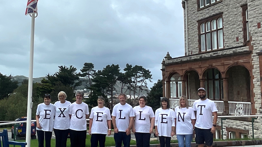 A group of nine Landudno Centre staff stood in front of the building wearing t-shirts with letters on which when all stood together spell "Excellent"