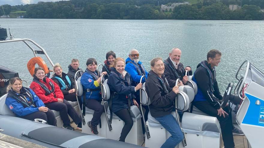 Blind veterans and staff smiling, while sat on a speed boat over a lake