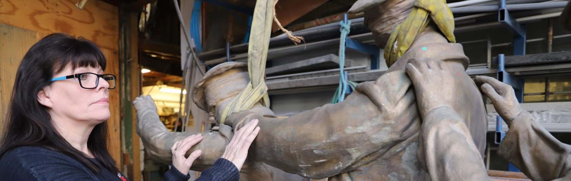 Artist Johanna Domke-Guyot placing her hands on the arms of the Victory Over Blindness statue