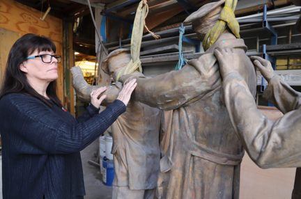 Artist Johanna Domke-Guyot placing her hands on the arms of the Victory Over Blindness statue