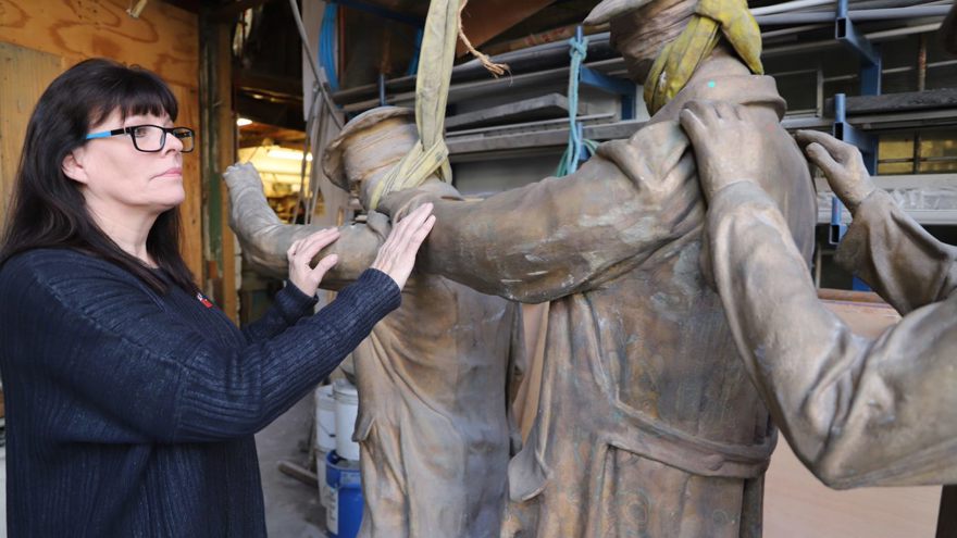 Artist Johanna Domke-Guyot placing her hands on the arms of the Victory Over Blindness statue