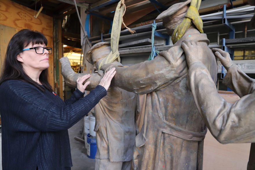 Artist Johanna Domke-Guyot placing her hands on the arms of the Victory Over Blindness statue