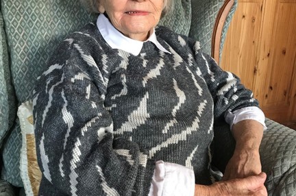 Photograph of blind veteran Neena, photographed at home sitting on an armchair