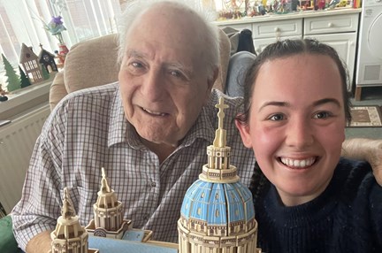 Blind veteran Maurice and volunteer Mia smile and look into camera while holding the cathedral model