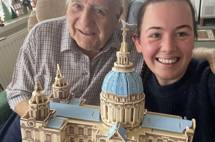 Blind veteran Maurice and volunteer Mia smile and look into camera while holding the cathedral model