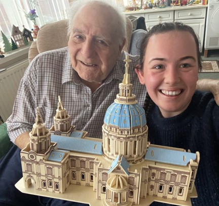 Blind veteran Maurice and volunteer Mia smile and look into camera while holding the cathedral model