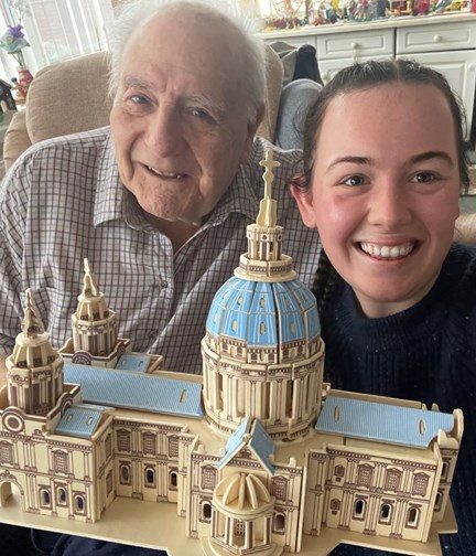 Blind veteran Maurice and volunteer Mia smile and look into camera while holding the cathedral model