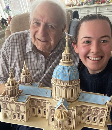 Blind veteran Maurice and volunteer Mia smile and look into camera while holding the cathedral model