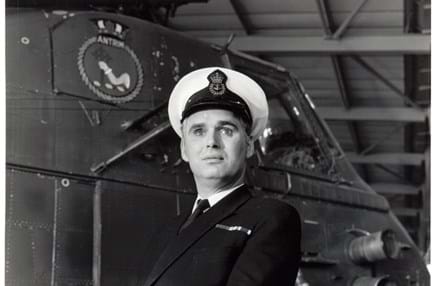 Photo of blind veteran, Terry Bullingham, in his Naval uniform standing in front of a vessel