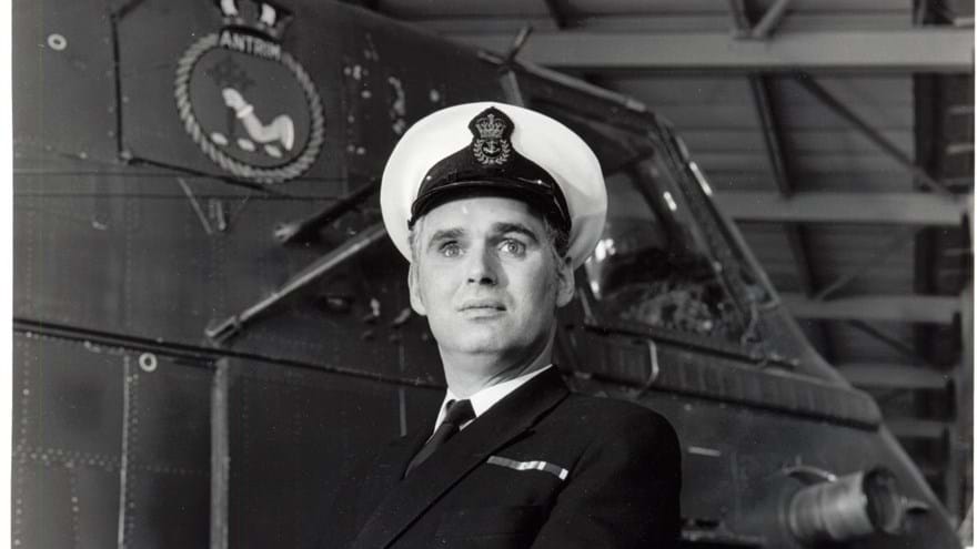 Photo of blind veteran, Terry Bullingham, in his Naval uniform standing in front of a vessel