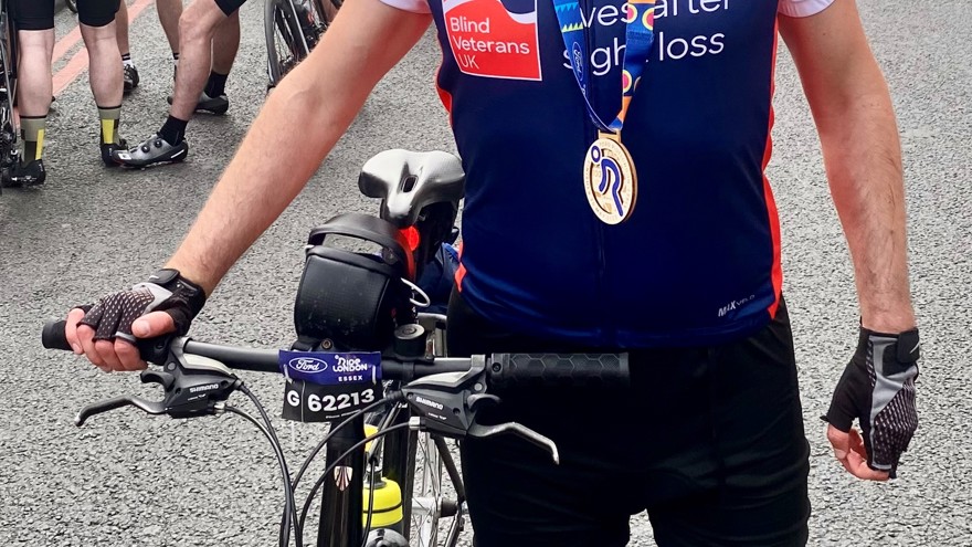 Rob standing with his bike and wearing his medal for completing the cycle