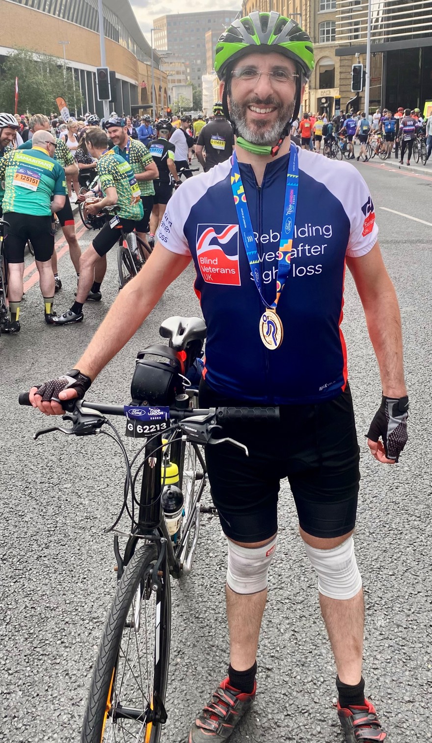 Rob standing with his bike and wearing his medal for completing the cycle