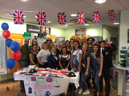 A group of staff members inside Specsavers huddled together wearing military fancy dress while fundraising
