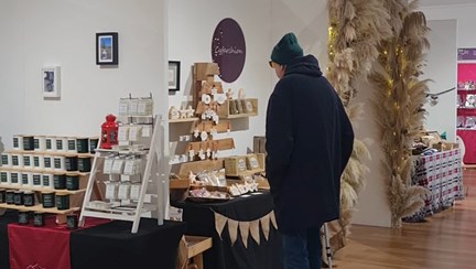 A man stands in front of a stall display handmade gifts and candles