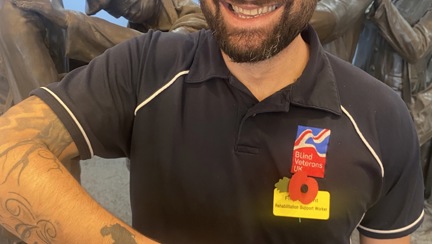 Member of staff wearing Blind Veterans UK t shirt and displaying his tattoo of a soldier with his head bowed down looking at a cross