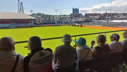 Picture taken from behind a group of veterans as they look down onto the rugby pitch to watch the concert