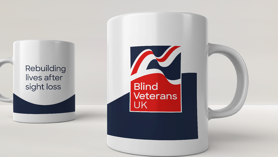 A white mug with a navy swoosh, Blind Veterans UK logo and tagline "rebuilding lives after sight loss"