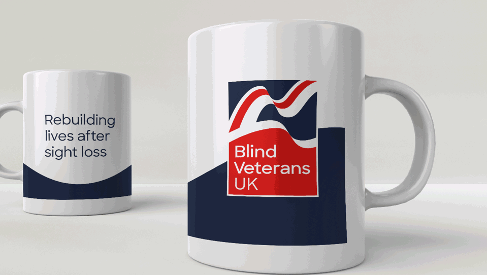 A white mug with a navy swoosh, Blind Veterans UK logo and tagline "rebuilding lives after sight loss"