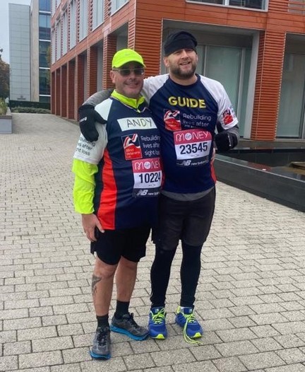 Blind veteran Andy and his guide, smiling, wearing Blind Veterans UK running tops